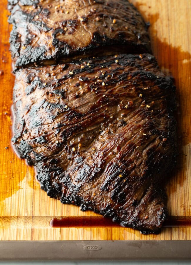 Seared steak resting on a wooden cutting board.