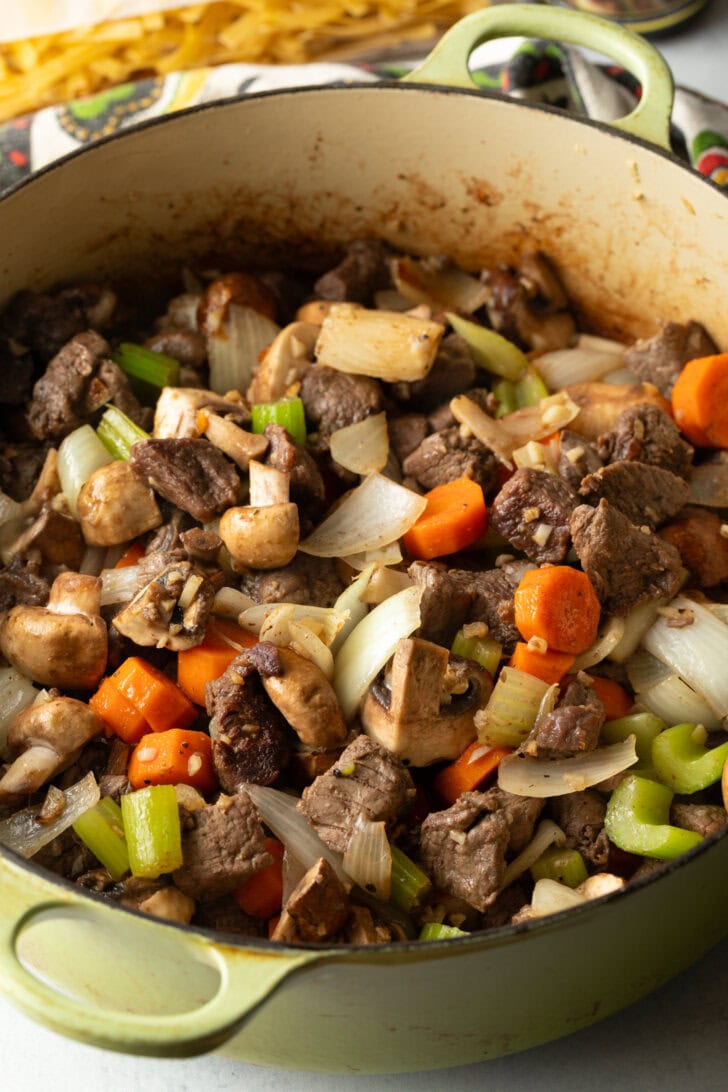 Searing beef chunks and veggies in a large cooking pot.