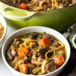 White bowl of noodle soup with meat and veggies.