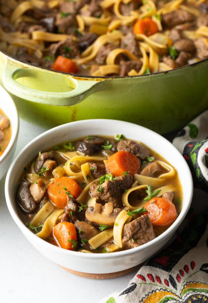 White bowl of noodle soup with meat and veggies.