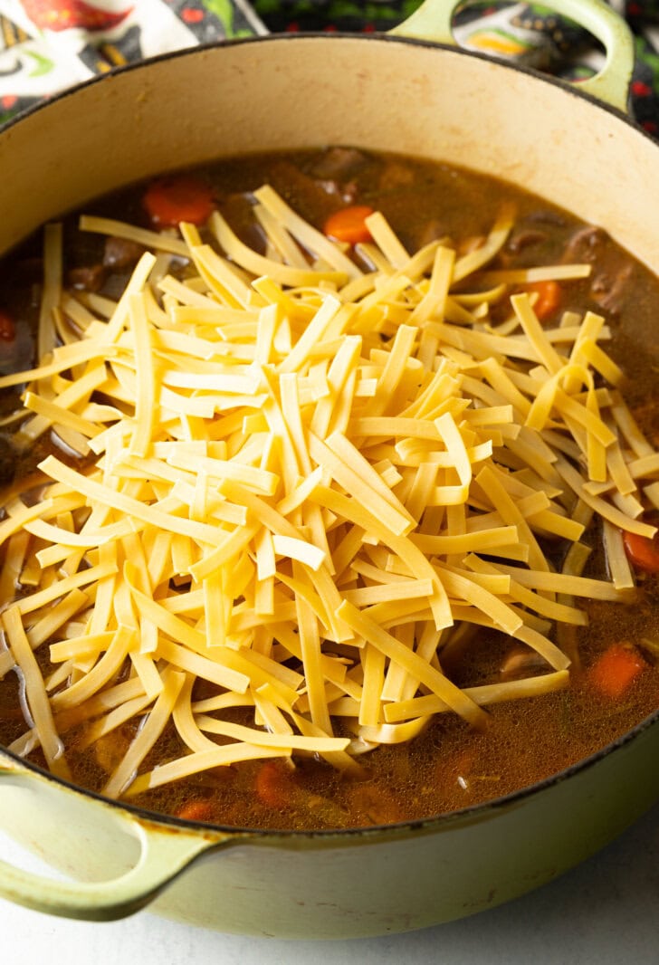 Adding noodles to the soup pot.