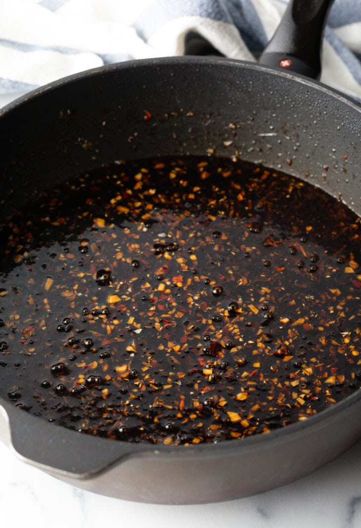 Brown teriyaki sauce in a deep black skillet.