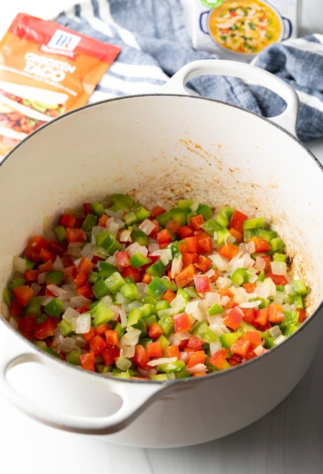 Diced bell pepper and onion in a white cooking pot.