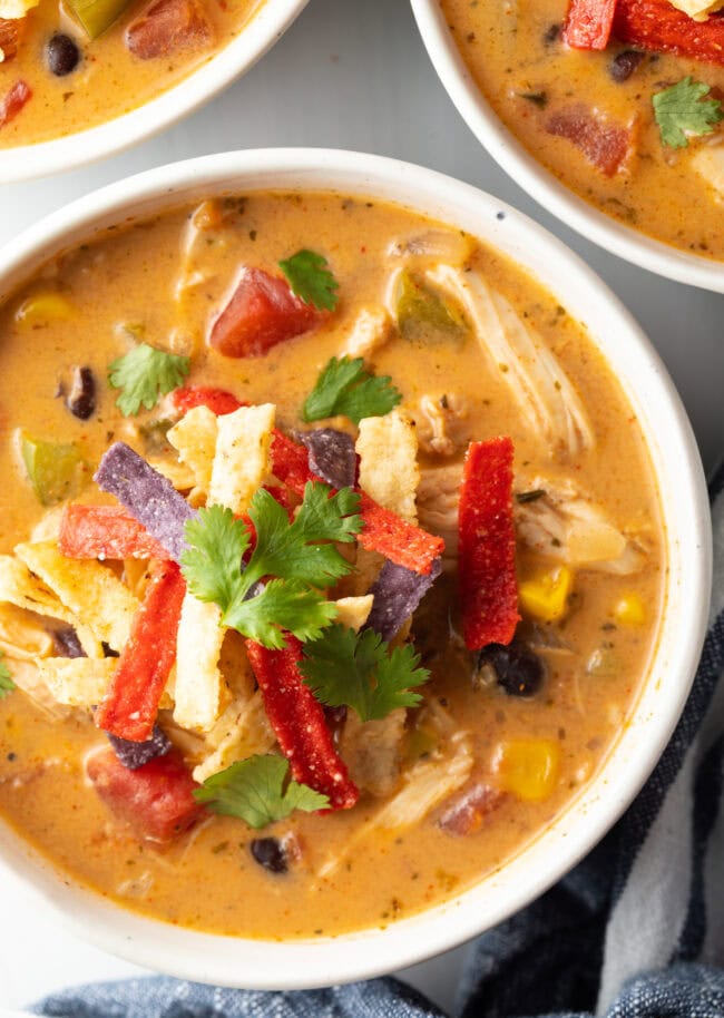 Top down view bowl of slow cooker chicken taco soup, garnished with fresh cilantro and tortilla strips.