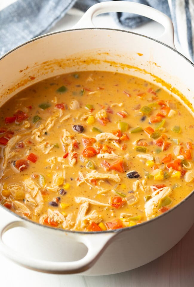 Creamy chicken, bean, and corn soup cooking in a white pot.