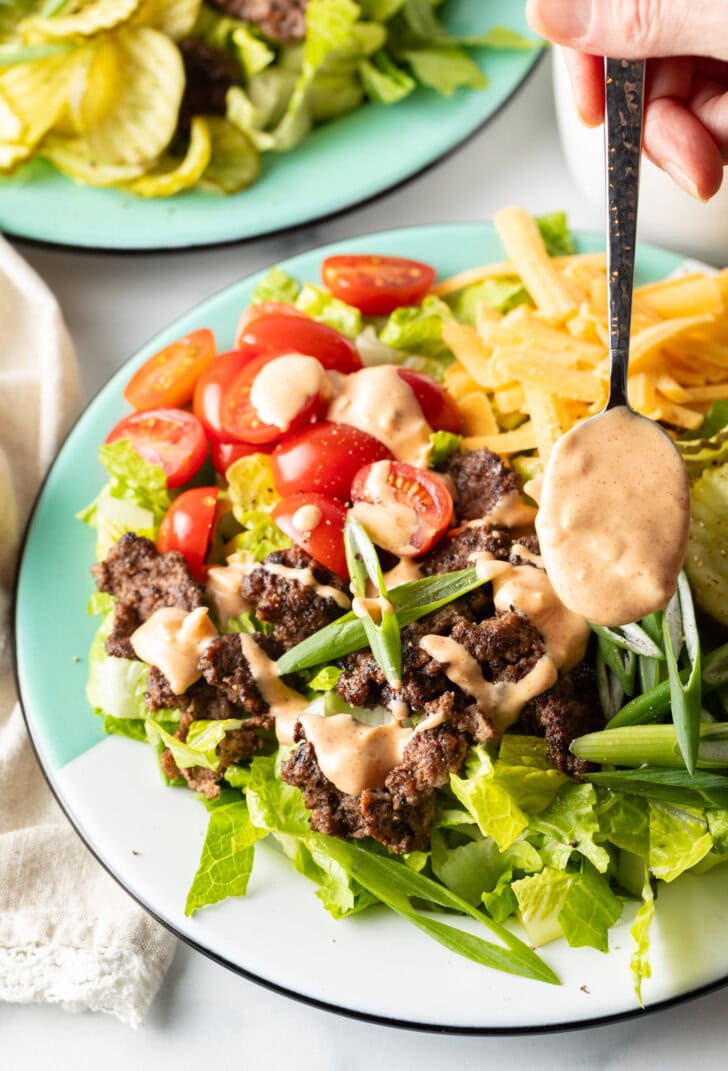 Spoonful of creamy Big Mac sauce being drizzled over the burger salad.