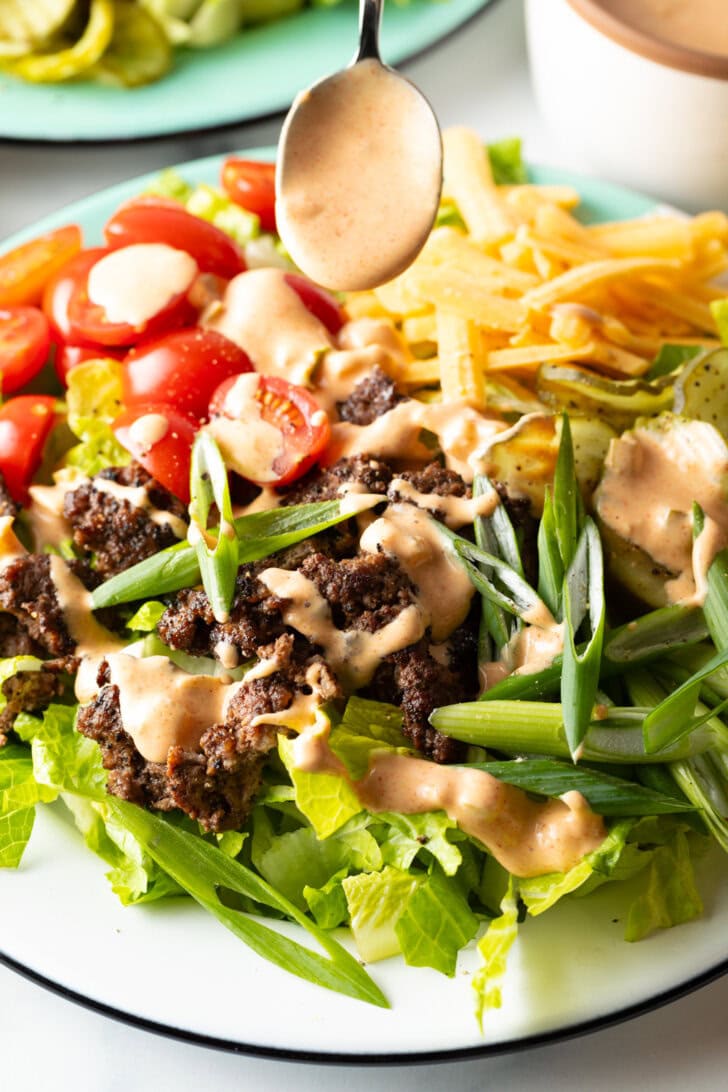 Spoonful of creamy Big Mac sauce being drizzled over the burger salad.