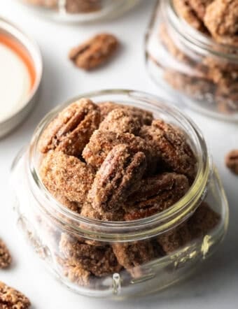 Close view of a glass jar overflowing with candied pecans.