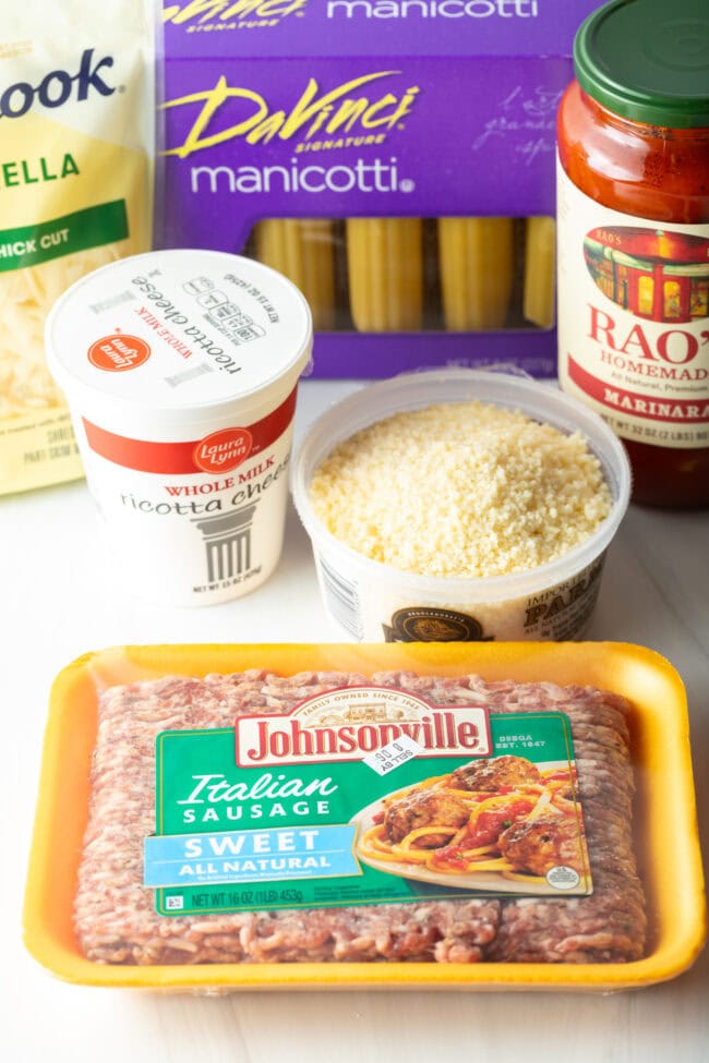 Recipe ingredients in their own containers: Package of sweet Italian sausage, ricotta cheese, parmesan, tomato sauce, shredded mozzarella, and no-boil noodles.