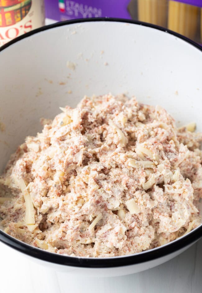 Cheese and meat filling ingredients combined in a large white bowl.