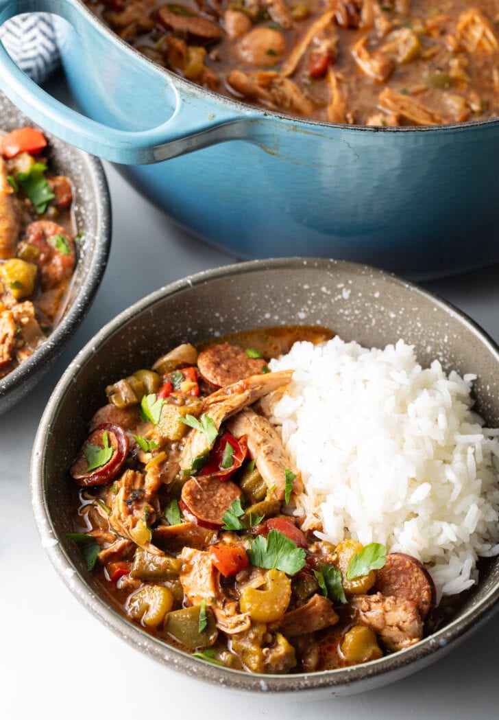 Bowl of chicken sausage gumbo with a scoop of white rice.