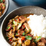 Bowl of chicken sausage gumbo with a scoop of white rice.