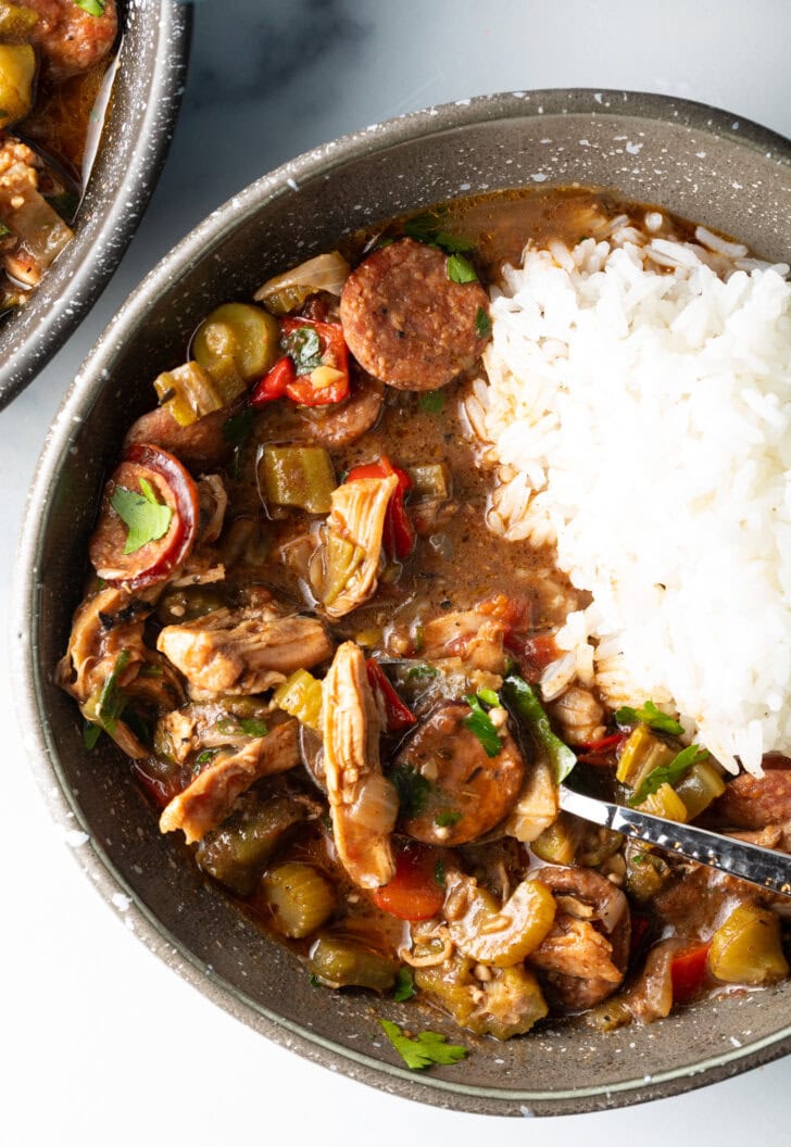 Bowl of chicken sausage gumbo with a scoop of white rice.