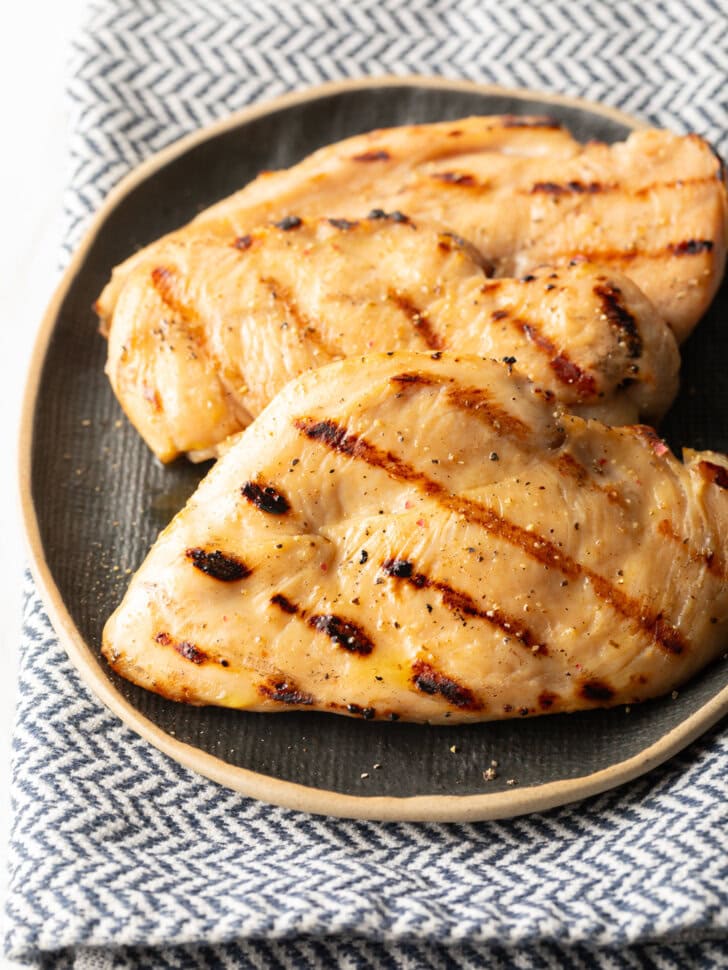 Two grilled chicken breasts on a gray plate.