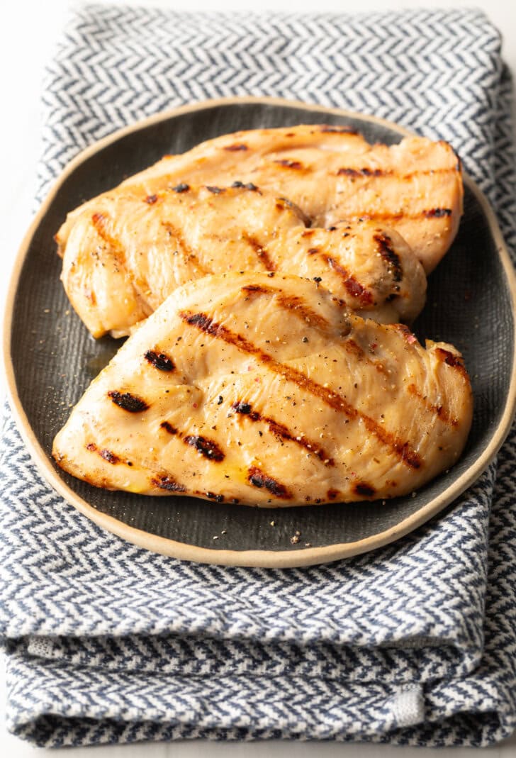 Two grilled chicken breasts on a gray plate.