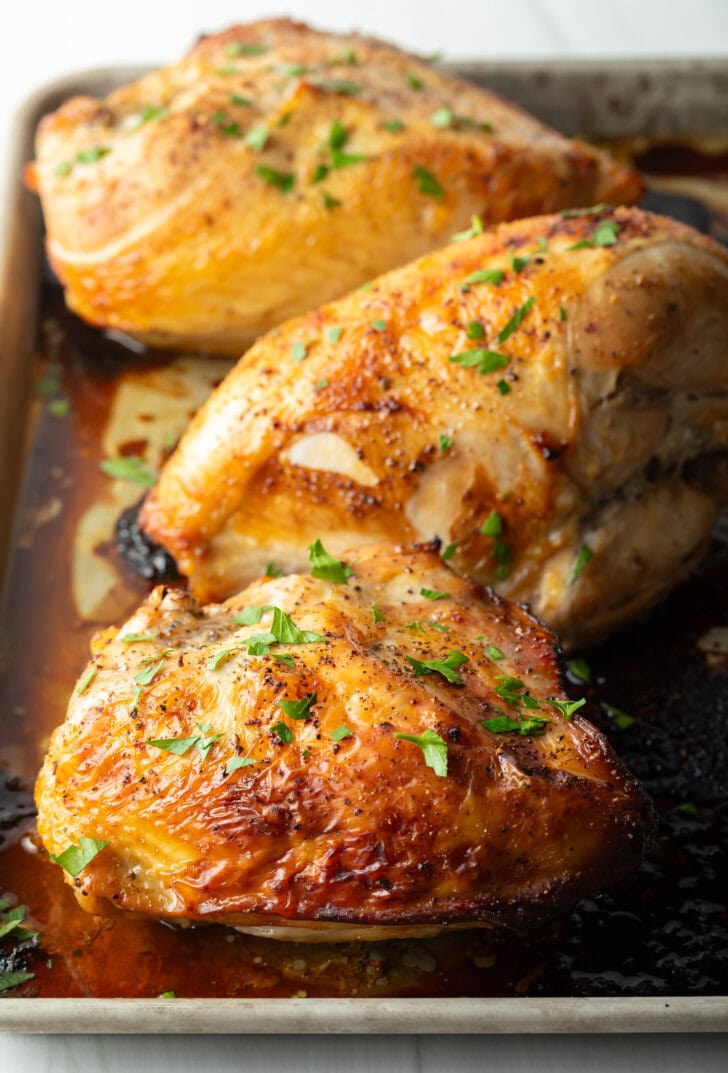 Cooked chicken breasts on a baking sheet.
