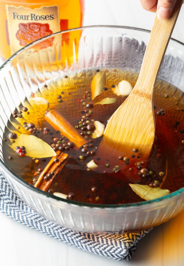 Using a wooden spoon to stir the brine in a glass bowl.