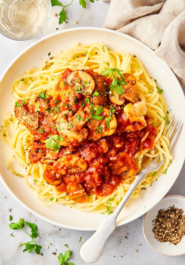 Chicken Cacciatore Recipe on a bed of noodles on a white plate.