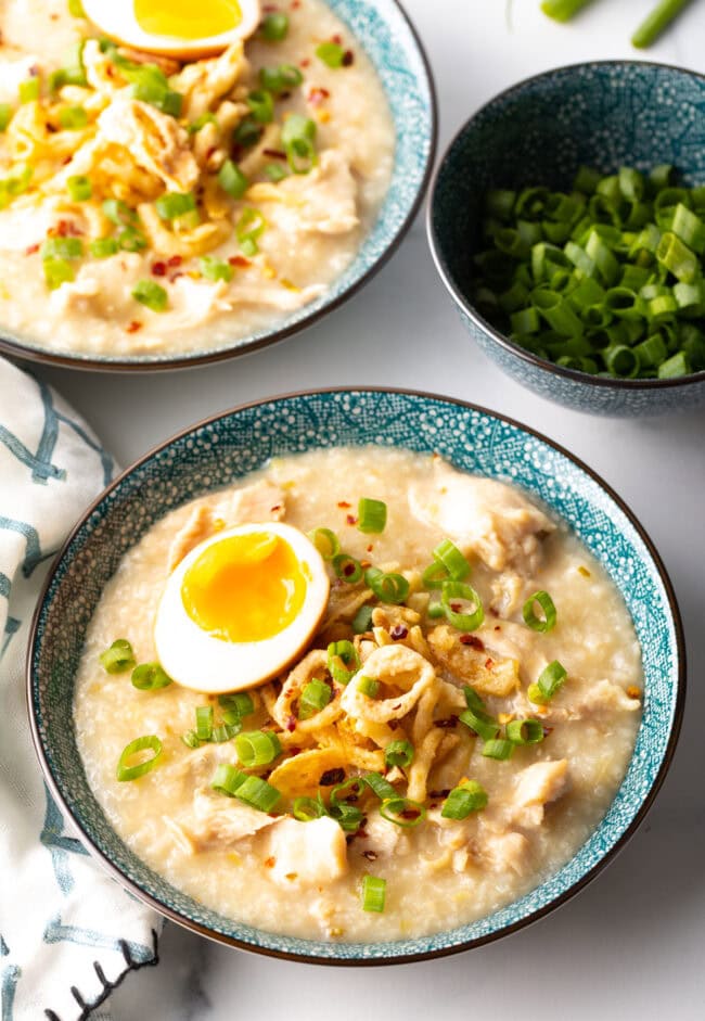 Top down soft boiled egg and goodies on top of rice porridge. Hero shot of jook recipe.