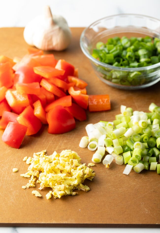 Piles of chopped green onion, garlic, and red pepper.