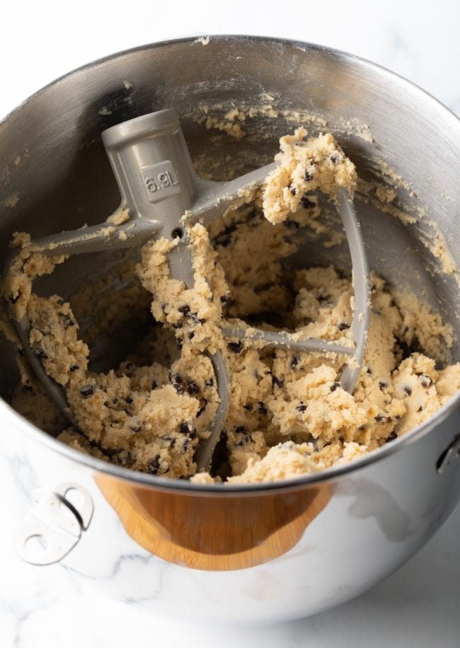 standing mixer bowl and paddle with chocolate chip and walnut raw cookie dough