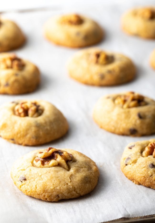 baked chocolate chip walnut cookies on parchment on a baking sheet