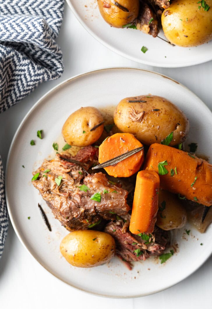 White plate with serving of tender beef, carrots, and whole baby potatoes.