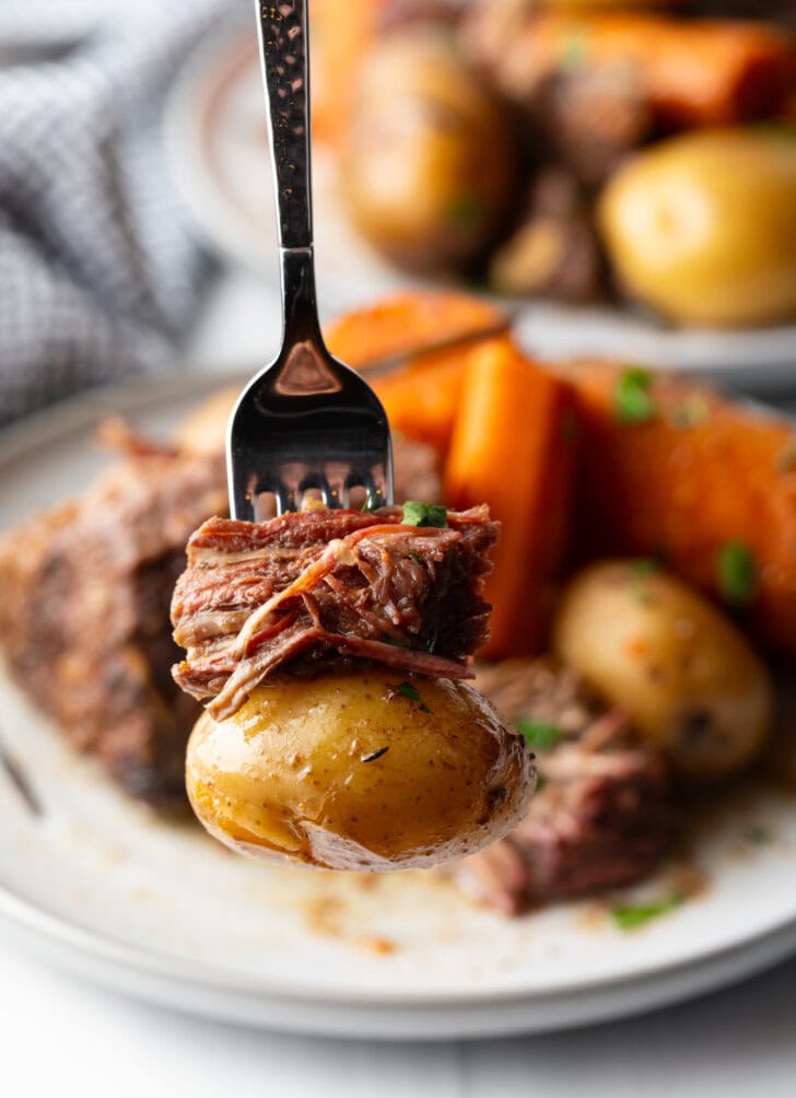 Fork is showing a bite of potato and chuck roast to the camera.