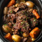 Pot roast cooked in a crock pot, with baby potatoes and large carrot chunks.