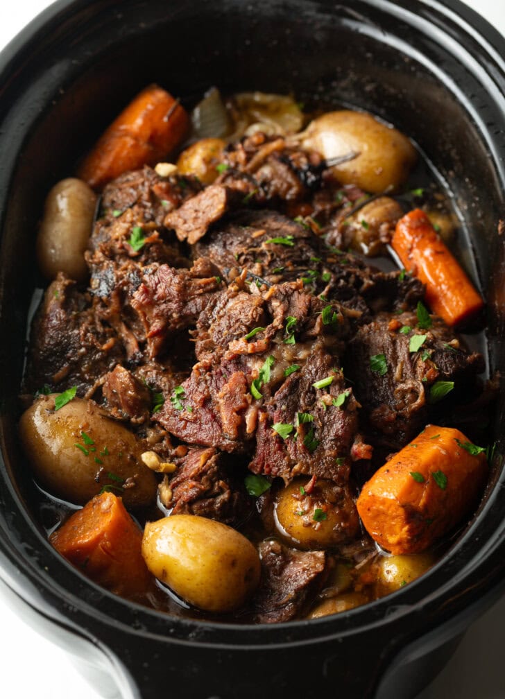 Pot roast cooked in a crock pot, with baby potatoes and large carrot chunks.
