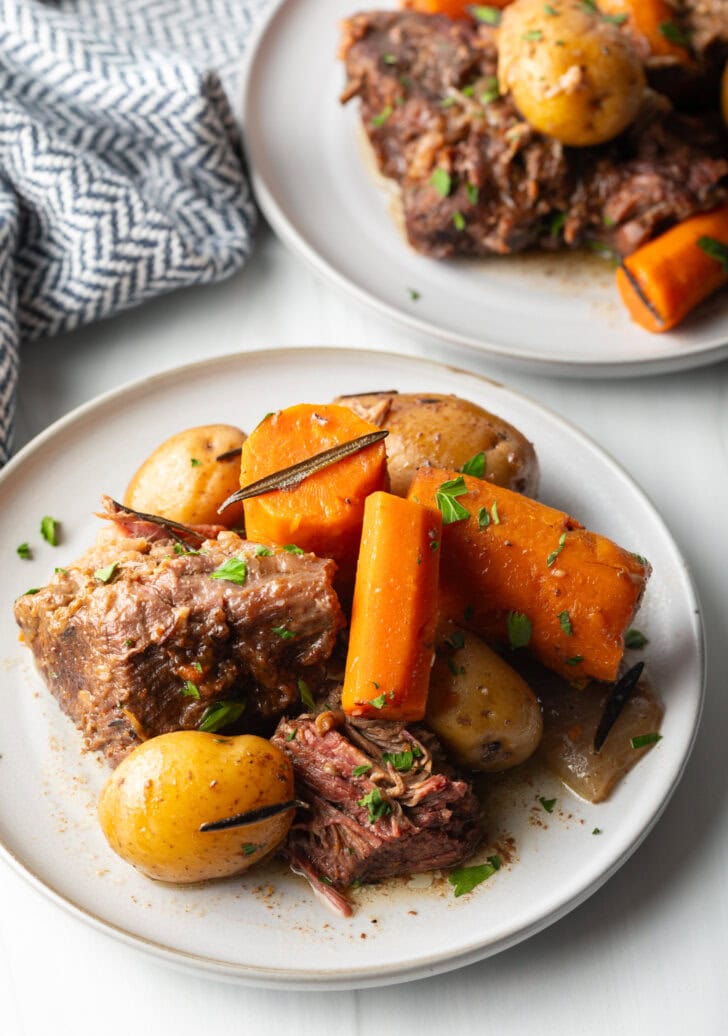 White plate with serving of tender beef, carrots, and whole baby potatoes.