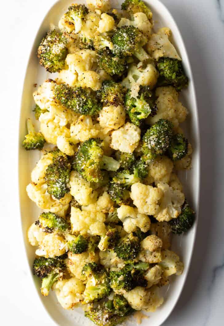 White oval platter loaded with roasted broccoli and cauliflower florets.
