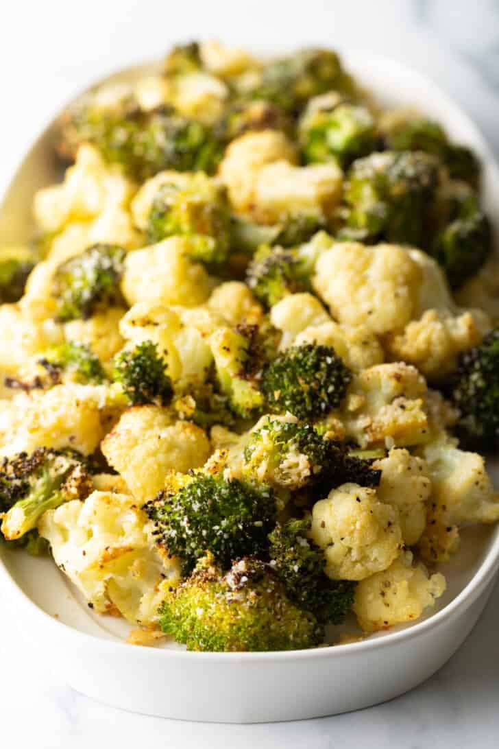 White oval platter loaded with roasted broccoli and cauliflower florets.
