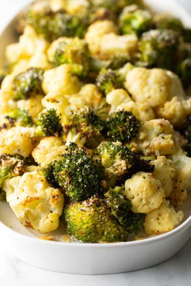 White oval platter loaded with roasted broccoli and cauliflower florets.