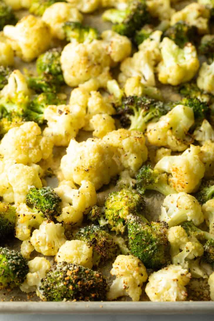 Baking sheet loaded with oven roasted cauliflower florets and broccoli florets.