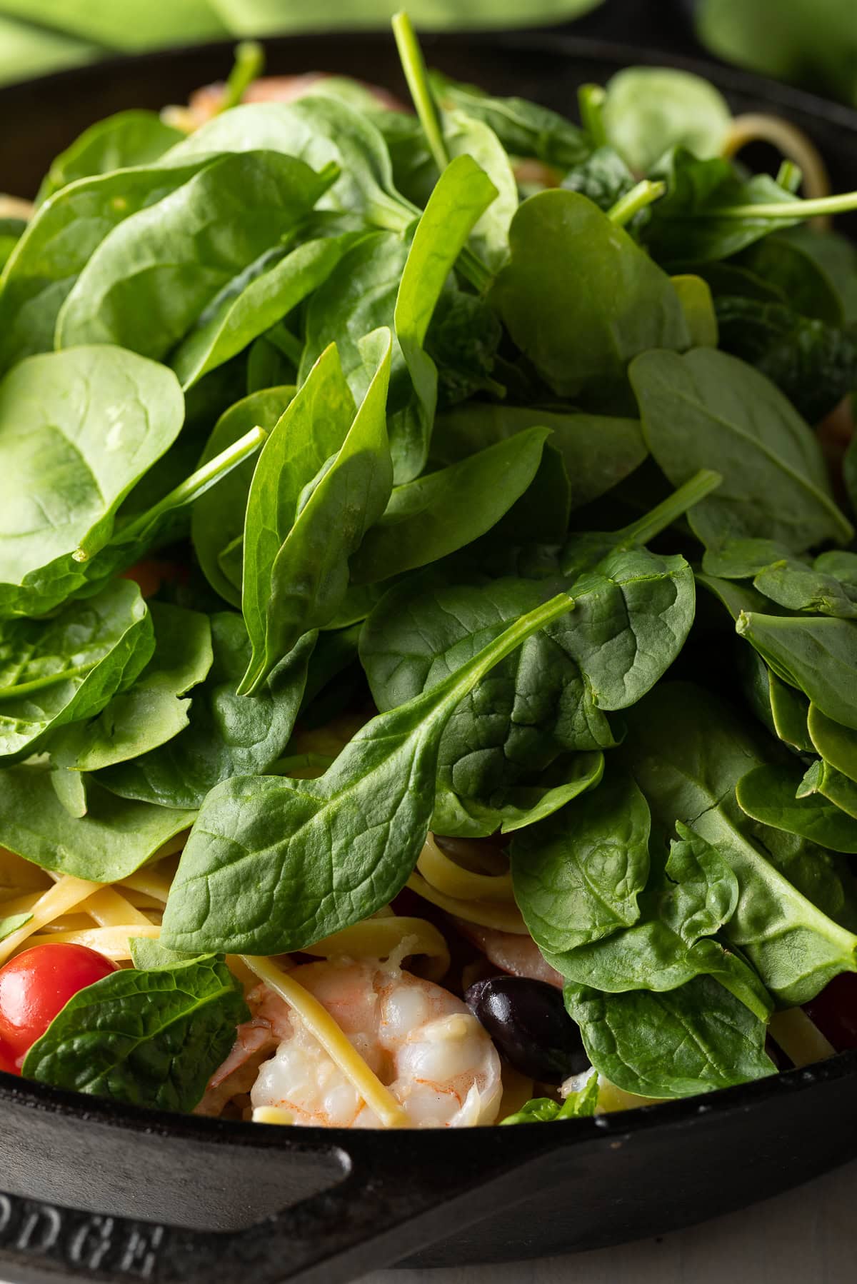 Spinach being added at the end of cooking this Mediterranean Shrimp Pasta.