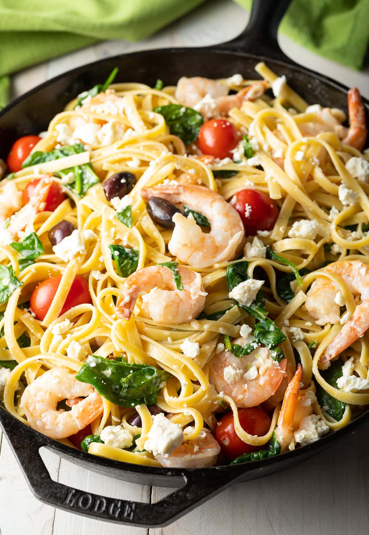 Mediterranean Shrimp Pasta in a cast iron skillet with shrimp, olives, tomatoes, spinach and feta. 