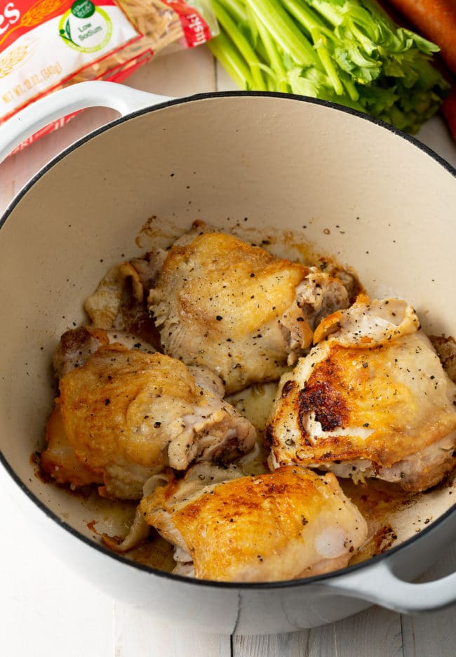 Browned chicken thighs in a dutch oven.