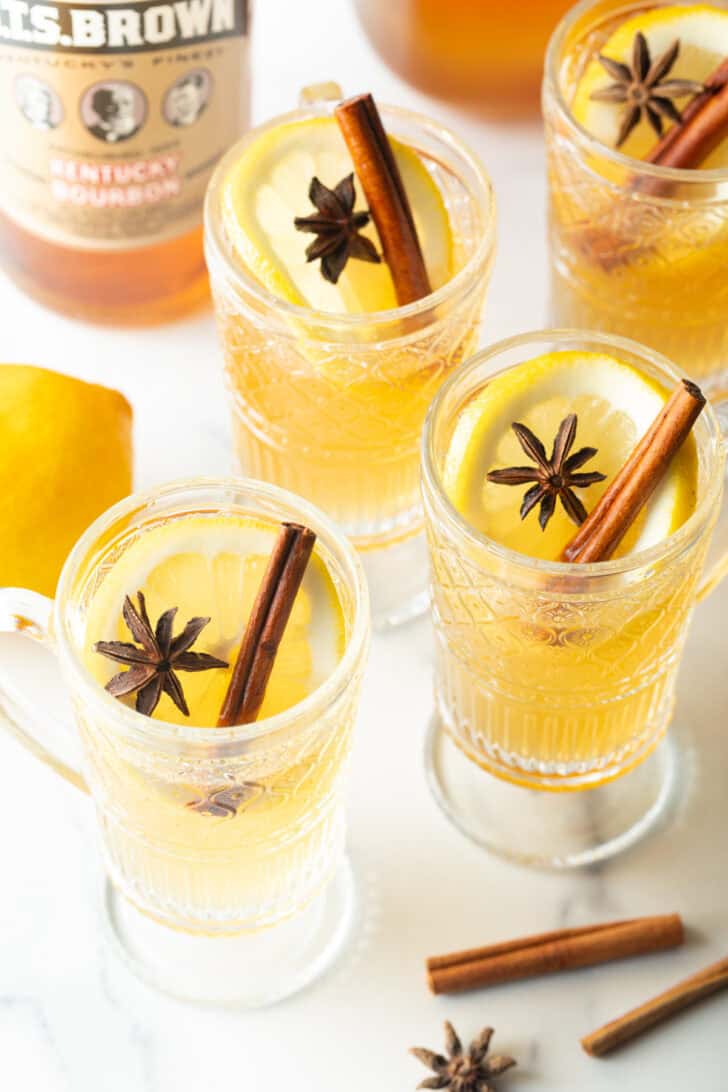 3 glasses with yellow tea, garnished with a whole star anise and stick of cinnamon.