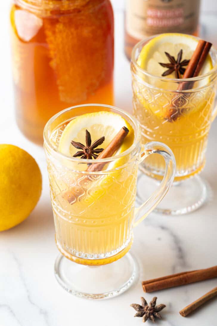 Glass handled mug with hot toddy, garnished with star anise and a cinnamon stick.