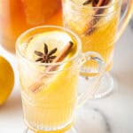 2 glass handled mugs with hot toddy, garnished with star anise and a cinnamon stick.
