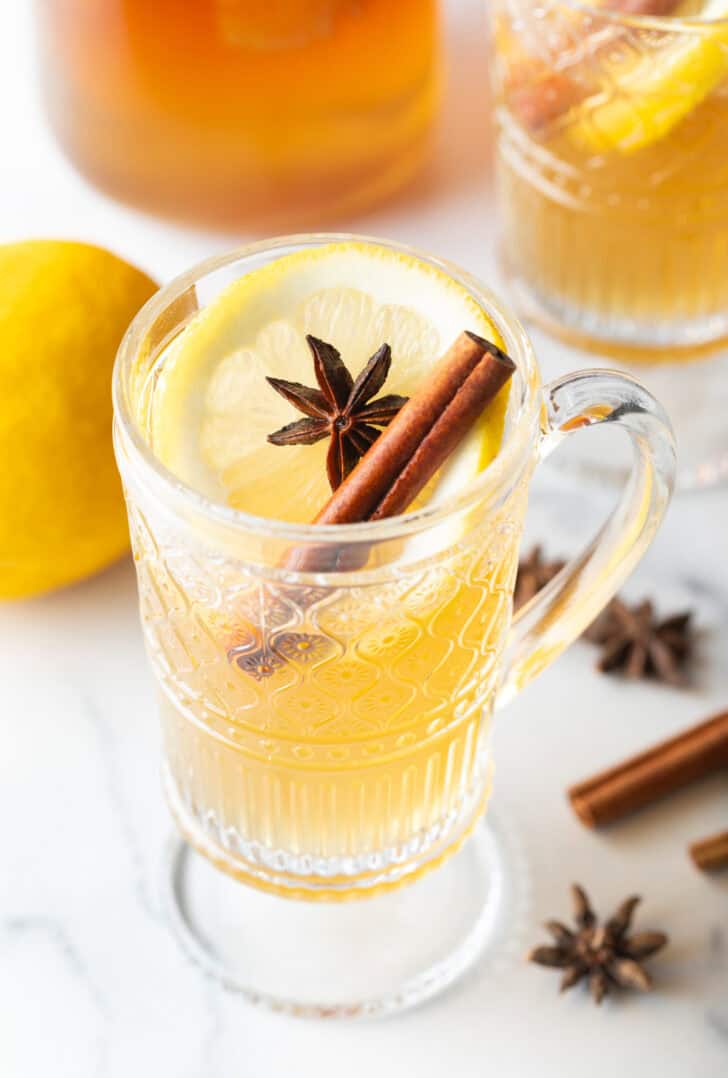 Glass handled mug with hot toddy, garnished with star anise and a cinnamon stick.