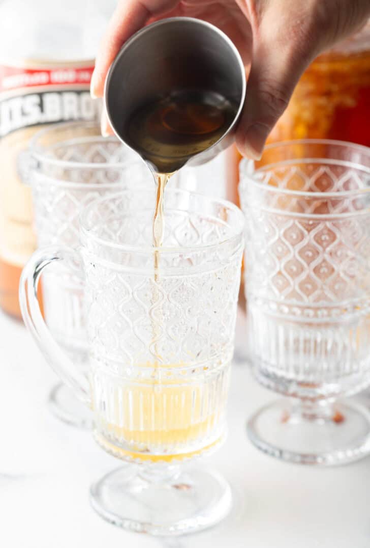 Add alcohol from a metal jig into a clear glass with a handle.