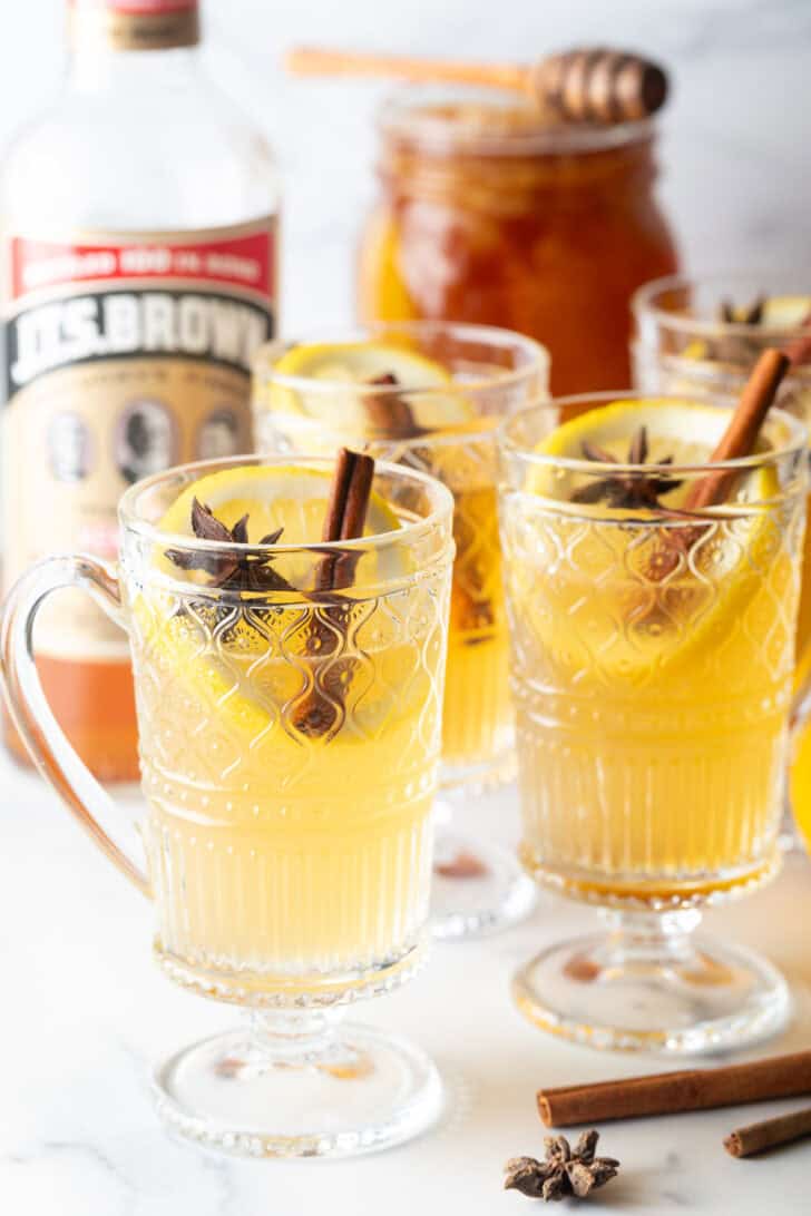 3 glasses with yellow tea, garnished with a whole star anise and stick of cinnamon.