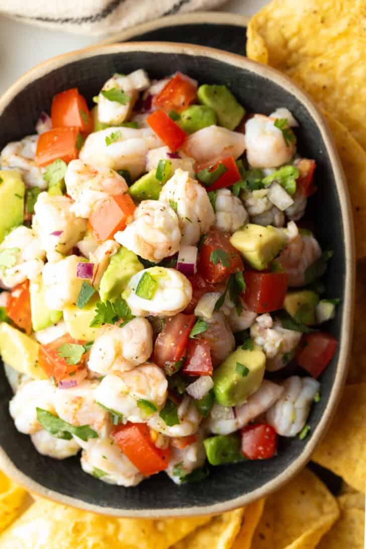 How to Make Shrimp Ceviche - Top down view yellow bowl with shrimp ceviche. The bowl is surrounded by tortilla chips.