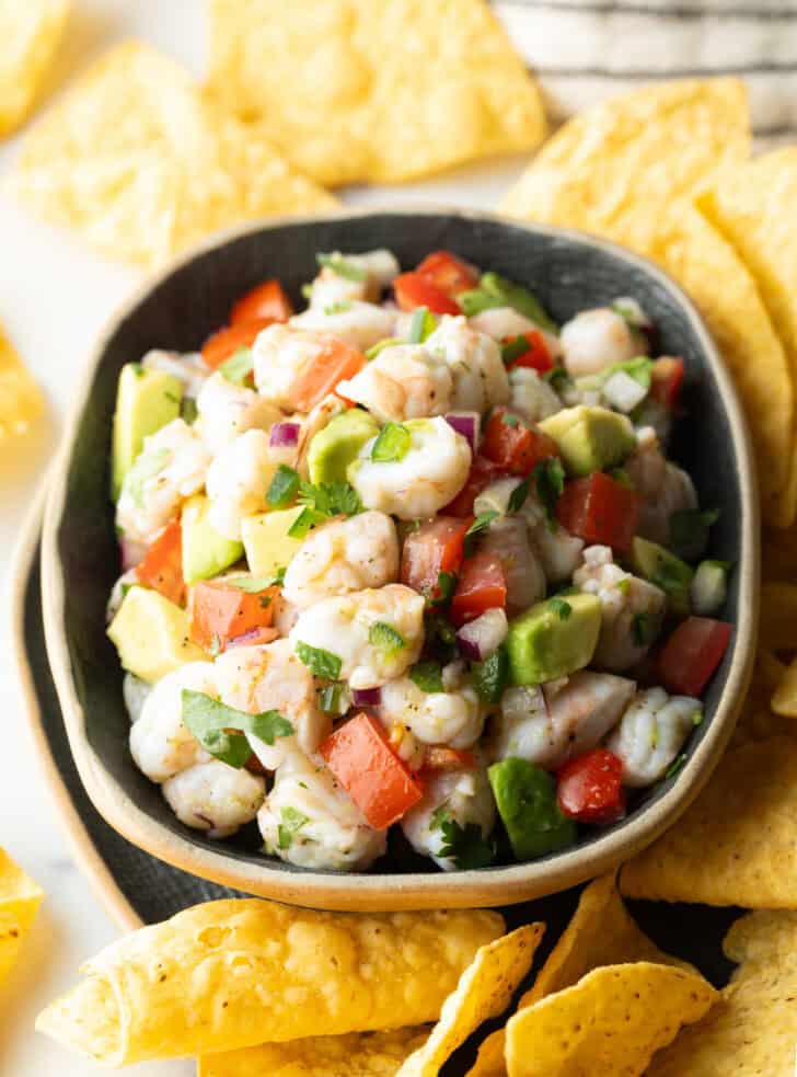 How to Make Shrimp Ceviche - Top down view yellow bowl with shrimp ceviche. The bowl is surrounded by tortilla chips.