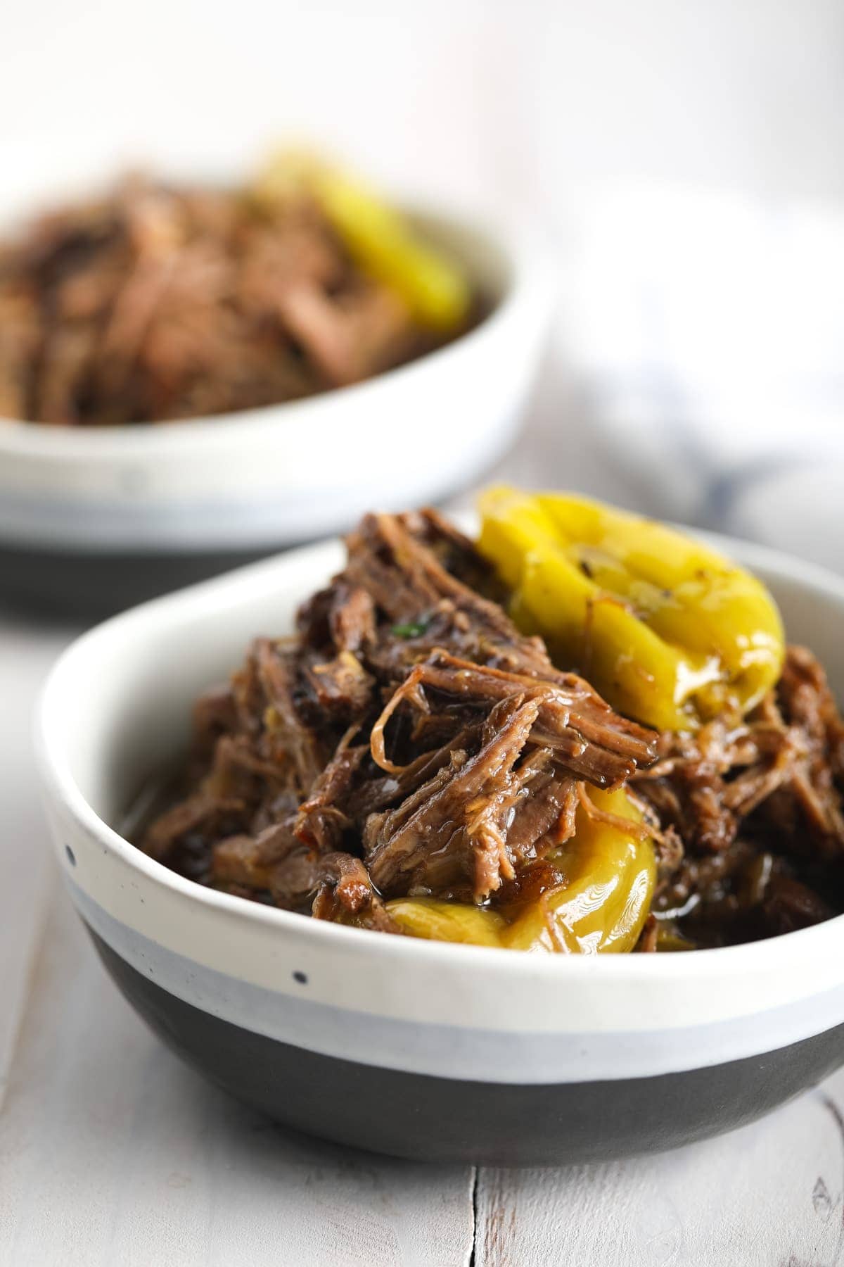 Italian-style shredded beef in a bowl with pepperoncinis. 
