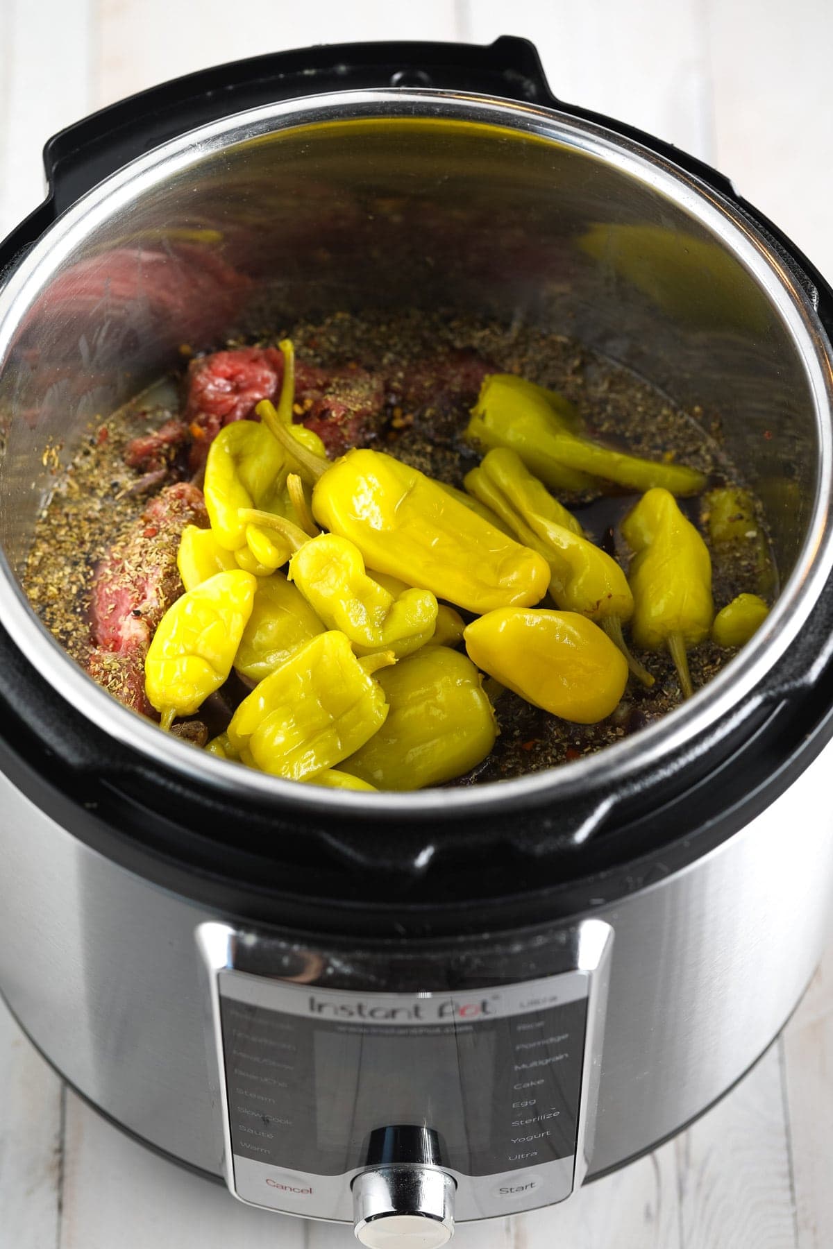 Pepperoncinis and spices added on top of the meat in the Instant Pot. 
