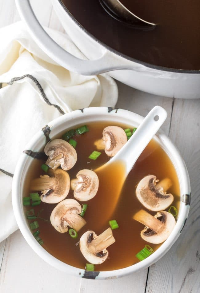 Overhead shot of Japanese clear soup in a bowl with mushrooms and scallions.