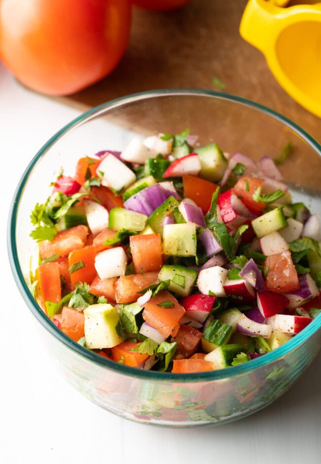 Chopped kachumber Indian cucumber salad in a glass bowl.